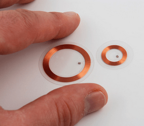 Fingers holding a small RFID tag